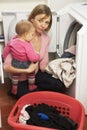 Woman Doing Laundry And Holding Daughter Royalty Free Stock Photo