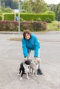 A woman is doing leash her two dogs