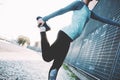 Woman doing legs warming exercise on the street, safety stretch before urban workout