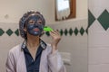 Woman doing a mud mask on her face with a scoop Royalty Free Stock Photo