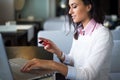 Woman doing online shopping at cafe, holding credit card typing numbers on laptop computer side view