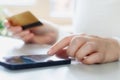 Woman doing online shopping using debit card and mobile. Female hands holding credit card over a mobile sitting at a Royalty Free Stock Photo