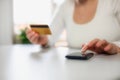 Woman doing online shopping using debit card and mobile. Female hands holding credit card over a mobile sitting at a Royalty Free Stock Photo