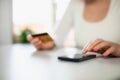 Woman doing online shopping using debit card and mobile. Female hands holding credit card over a mobile sitting at a Royalty Free Stock Photo