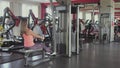 Girl shakes her arm muscles on training simulator in the gym or fitness club. Woman doing physical jerks and exercises