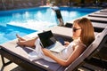 Woman doing remote multitasking work with multiple electronic internet devices on swimming pool beach bed. Freelancer