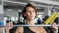 Woman is doing set of reps exercise with barbell lifting it over the head in gym.