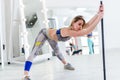 Woman doing stretching exercise for hamstrings and back leaning forward holding barbell in one hand