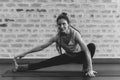 Woman doing stretching on a yoga mat against brick wall black and white photography Royalty Free Stock Photo