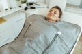 woman doing whiskey swaddling procedure in thermal blanket