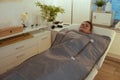 woman doing whiskey swaddling procedure in thermal blanket