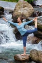 Woman doing yoga asana Natarajasana outdoors at waterfall Royalty Free Stock Photo