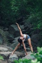 Woman doing yoga asana parivritta trikonasana - pose of the rotating triangle. Yoga in nature.