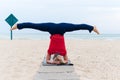 Woman doing yoga asana upavishtha konasana shirshasana, Bound Angle Pose in Head Stand on sea background