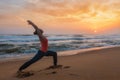 Woman doing yoga asana Virabhadrasana 1 Warrior Pose on beach on Royalty Free Stock Photo