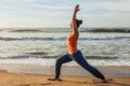 Woman doing yoga asana Virabhadrasana 1 Warrior Pose on beach on Royalty Free Stock Photo