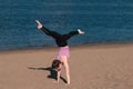 Woman doing yoga on the beach by the river in the city. Beautiful view. Handstand. Royalty Free Stock Photo