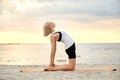 woman doing yoga camel pose on beach Royalty Free Stock Photo