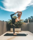 Woman doing yoga dancer pose on the rooftop