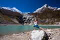 Woman is doing yoga excercises near big lake on the Manaslu circuit trak in Nepala Royalty Free Stock Photo