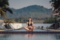 The Woman doing yoga exercise at poolside