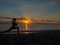 Woman doing yoga exercise during sunset on the beach. Royalty Free Stock Photo