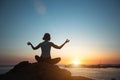 A woman doing yoga in the lotus pose meditating on the beach during sunset. Royalty Free Stock Photo