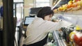 Woman with Down syndrome restocking fresh fruits in a grocery store