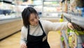 Woman with Down syndrome restocking goods in a grocery store on lower shelf