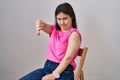 Woman with down syndrome wearing band aid for vaccine injection with angry face, negative sign showing dislike with thumbs down,