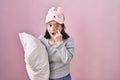 Woman with down syndrome wearing sleeping mask hugging pillow pointing to the eye watching you gesture, suspicious expression Royalty Free Stock Photo