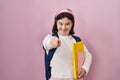 Woman with down syndrome wearing student backpack and holding books pointing to you and the camera with fingers, smiling positive Royalty Free Stock Photo