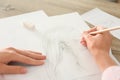 Woman drawing girl`s portrait with pencil on sheet of paper at wooden table Royalty Free Stock Photo