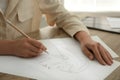 Woman drawing girl`s portrait with pencil on sheet of paper at wooden table, closeup Royalty Free Stock Photo