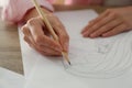 Woman drawing girl`s portrait with pencil on sheet of paper at wooden table, closeup Royalty Free Stock Photo