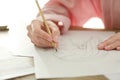 Woman drawing girl`s portrait with pencil on sheet of paper at wooden table Royalty Free Stock Photo