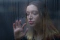 Woman drawing heart on foggy window on rainy day