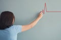 Woman drawing heartbeat with red chalk on wall. Royalty Free Stock Photo