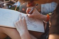 Woman draws letters in the park. Outline hand lettering in a sketchbook