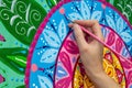 Woman draws a mandala, hand with a brush close-up