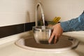 woman draws water from the tap into a saucepan