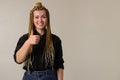 A happy woman, standing, with dreadlocks smiling and gesturing with a thumbs up Royalty Free Stock Photo