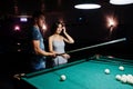 Woman in dress playing pool with a man in a pub Royalty Free Stock Photo