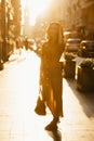 A woman in a dress with a plunging neckline holds a bag on the sunset in Spain Royalty Free Stock Photo