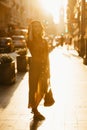 A woman in a dress with a plunging neckline holds a bag on the sunset in Spain Royalty Free Stock Photo