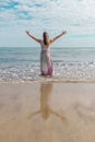 Woman in a dress in the sea enjoying her freedom with open arms