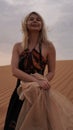 Woman in dress with a silk scarf, view of desert sand. Landscape vertical photo Royalty Free Stock Photo