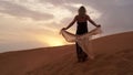 Woman in dress with a silk scarf, view of desert sand in sunset light. Landscape Royalty Free Stock Photo