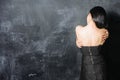 Woman in dress standing with back on black wall background with copy space Royalty Free Stock Photo