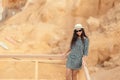 Woman in a dress is standing at the wooden fence on the beach